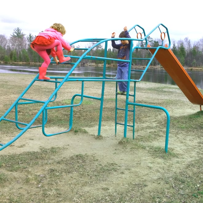 two kids climbing monkey bars at a playground