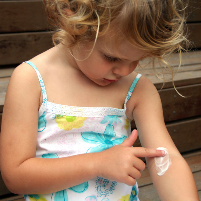 Child rubbing cream into her arm