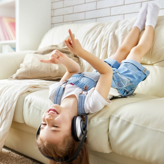 Girl lays on sofa listening to music