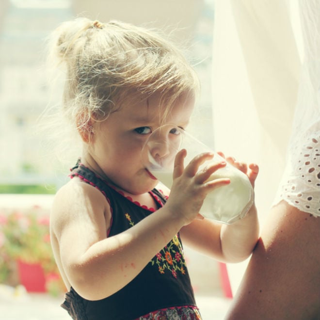 little girl drinks a glass of milk