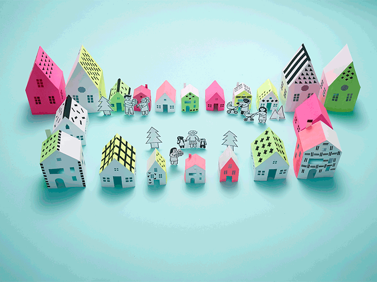 Paper people surrounded by paper houses