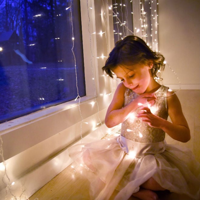 Little girl in a dress near twinkly lights