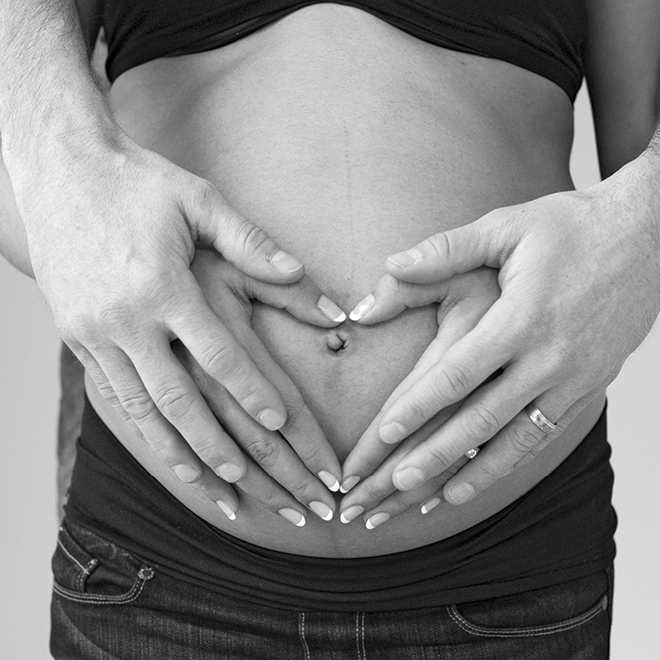 couple holding hands around pregnant belly