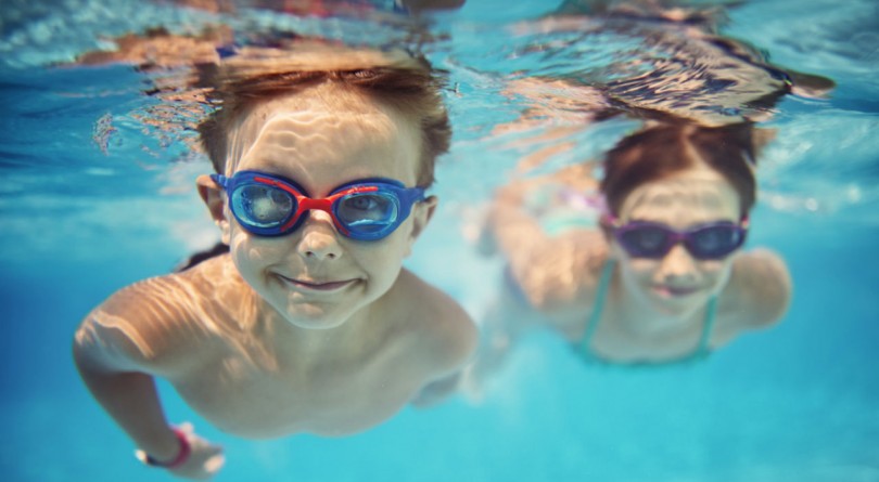 Two children swimming underwater with goggles on during March break