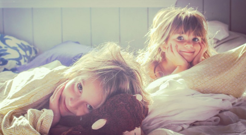 two kids lying in bed smiling