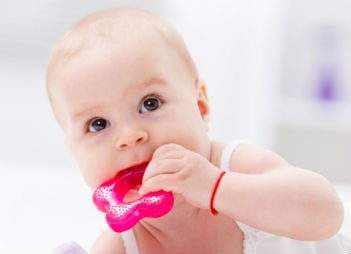 a teething baby chewing on a toy