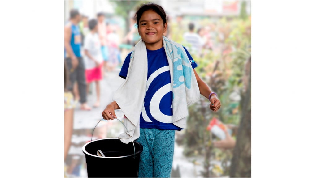 young girl carrying hygiene kit