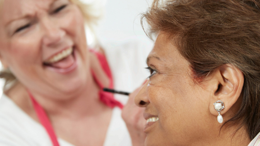 woman applies makeup to a cancer survivor