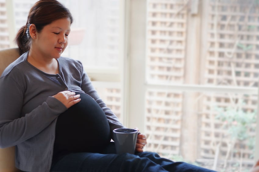 A pregnant woman drinking a cup of tea