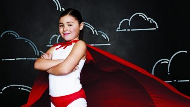 a little girl posing confidently in a superhero outfit