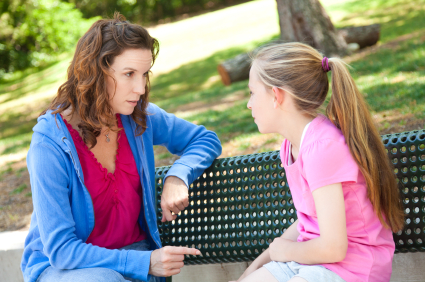 Photo of a mother talking to a girl on a bench