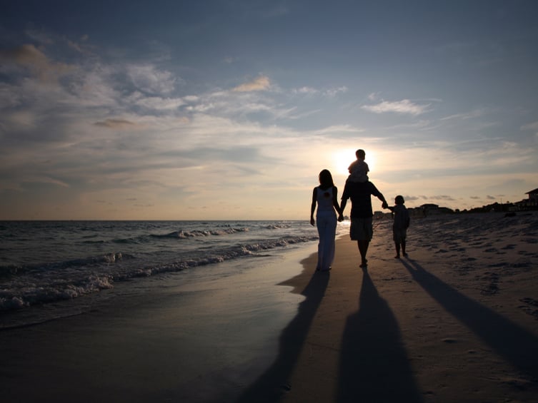Family walking on a beach at sunset
