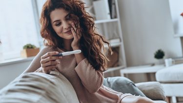 happy woman looks at positive pregnancy test