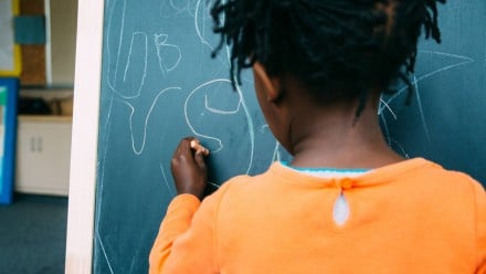 A little girl writing on a chalkboard