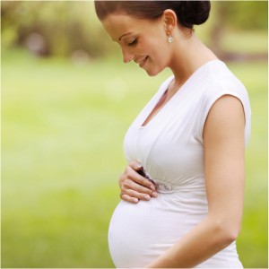 Pregnant woman standing outside in a white dress