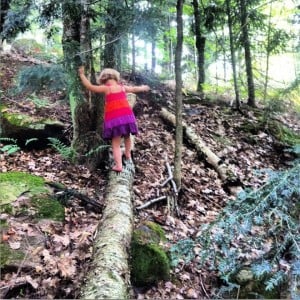 Photo of a child walking along a log in a forest