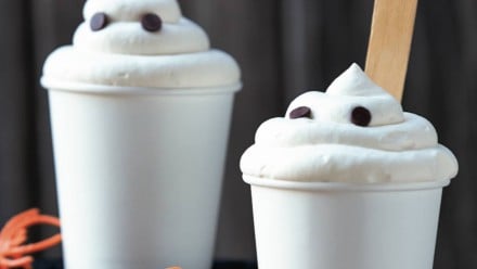 Two white cups with whipping cream and chocolate chips on top