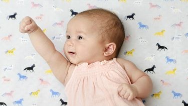 9 week old baby raising an arm in the air (resembling superman)