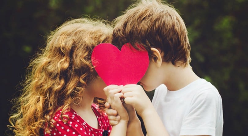 Two kids holding a heart that covers their face