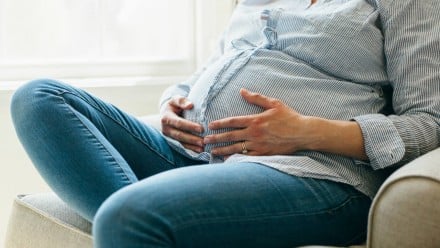 A pregnant woman sitting down and holding her belly