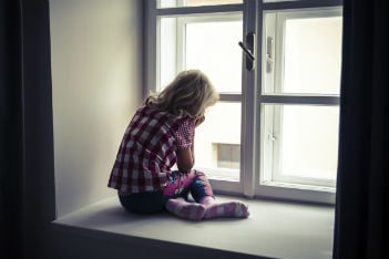 Sad child looking out a window