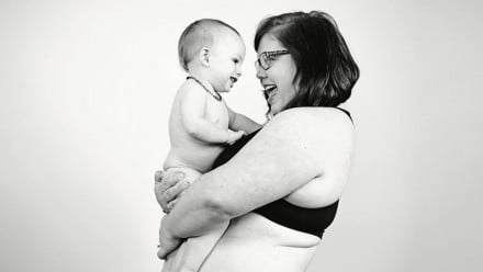 A woman in her underwear smiling at her baby