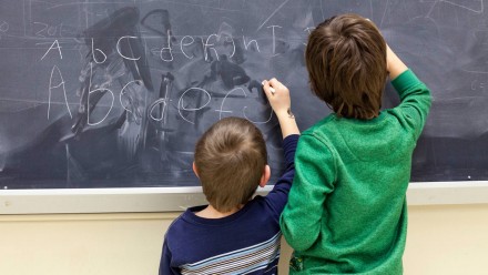 Two little boys writing on a chalkboard