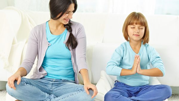 Mom and daughter both sitting cross-legged meditating