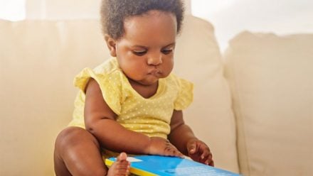 baby reading a book on the couch