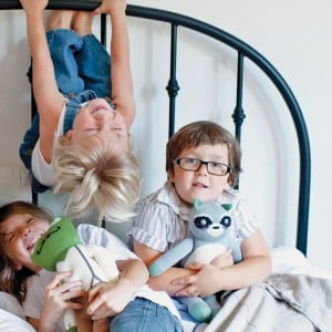 Photo of three kids playing on a bed