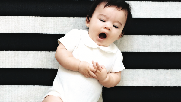A baby yawning on a black and white blanket