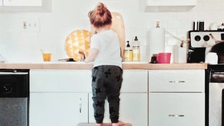 A little boy doing the dishes in the kitchen