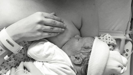 A black and white photo of a mom breastfeeding her newborn