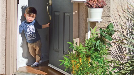 Little boy wearing an my aunt rock t-shirts at doorway of house