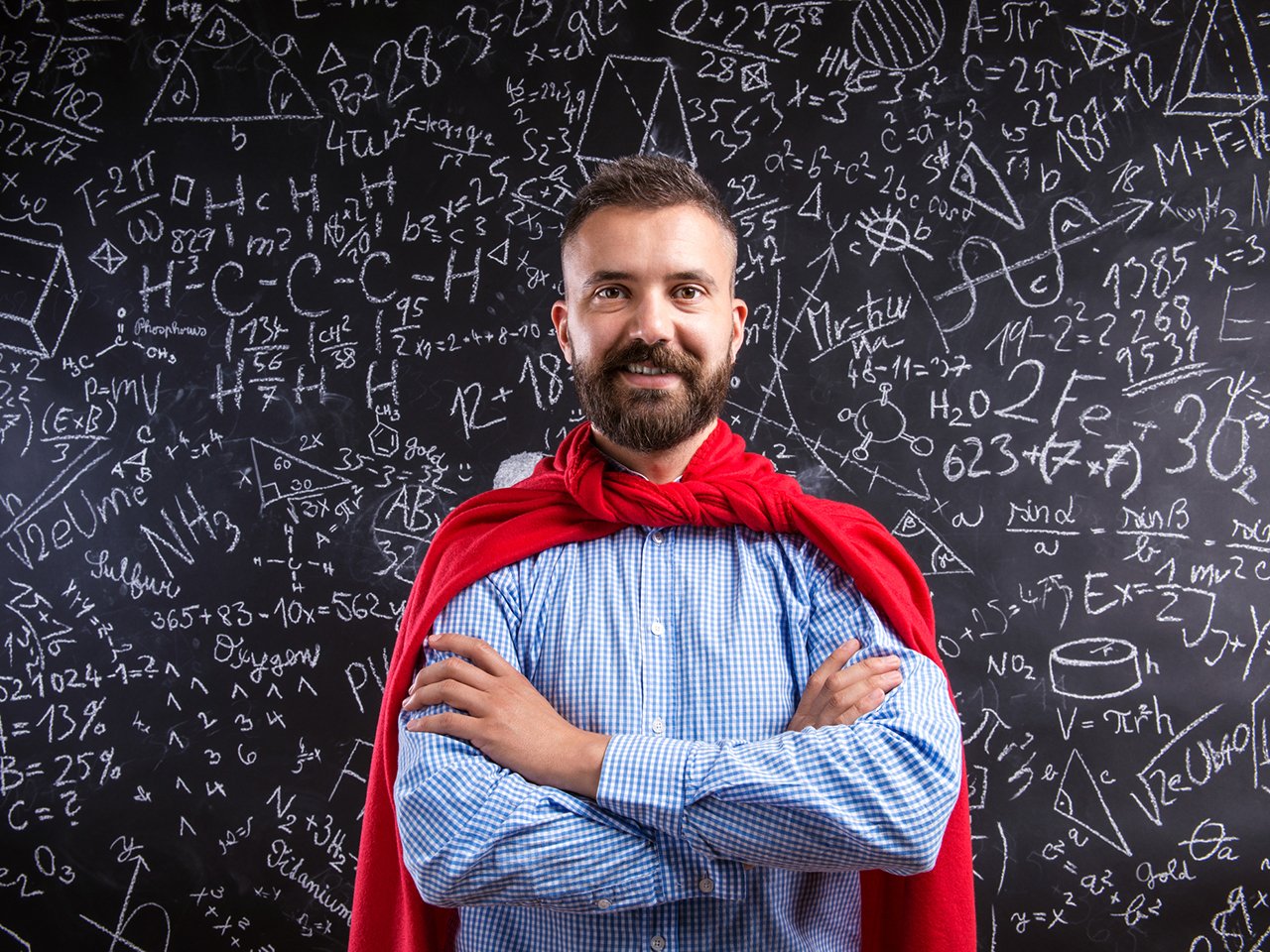 Teacher wearing red cape against black chalkboard