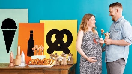 Man and pregnant woman standing near a table decorated for a coed baby shower