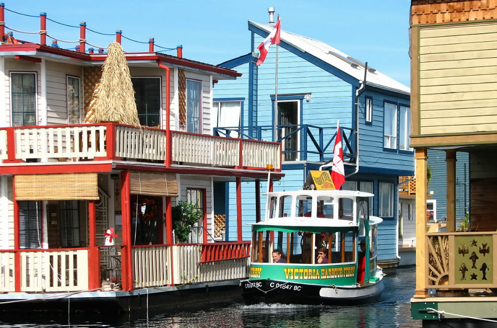 house boat sailing on a canal between brightly coloured houses