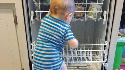 A baby climbing into the dishwasher