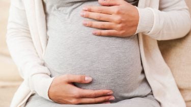 Pregnant woman sitting and holding her belly