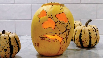 A carved pumpkin with marker drawn on it