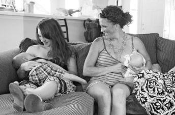 Two moms breastfeeding on a couch