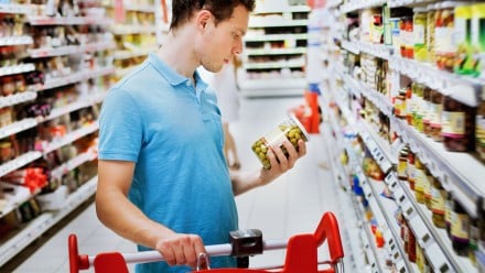 Man in the grocery store reading a label on a jar