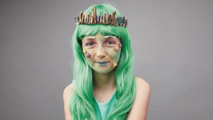 A girl with green hair and her face painted like a mermaid