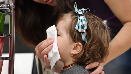 A person helping a child blow their nose