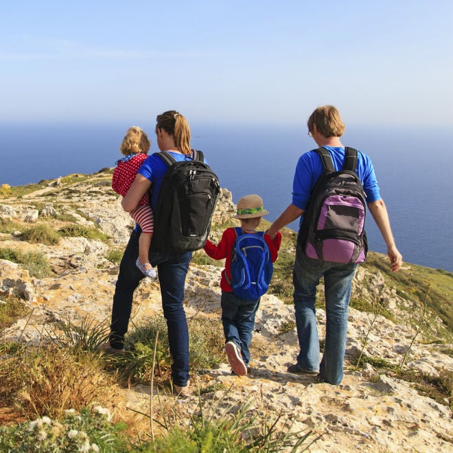 A mom, dad, and two young cliffs walk near a cliff-edge
