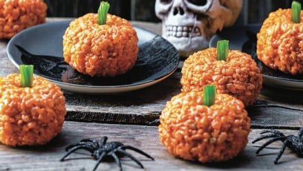 A black table with pumpkin shaped rice krispie treats