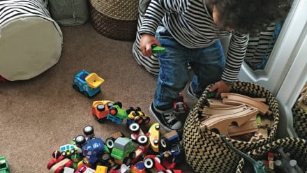 A little boy pulling trains out of a toy bin