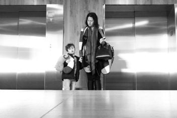 A woman holding a boy's hand in front of elevators.