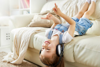 Girl lays on couch listening to music through headphones