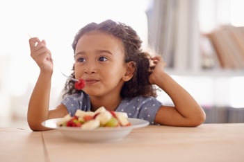 Little girl eating a bowl of sliced apples